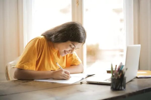 Girl in yellow shirt with laptop and paper